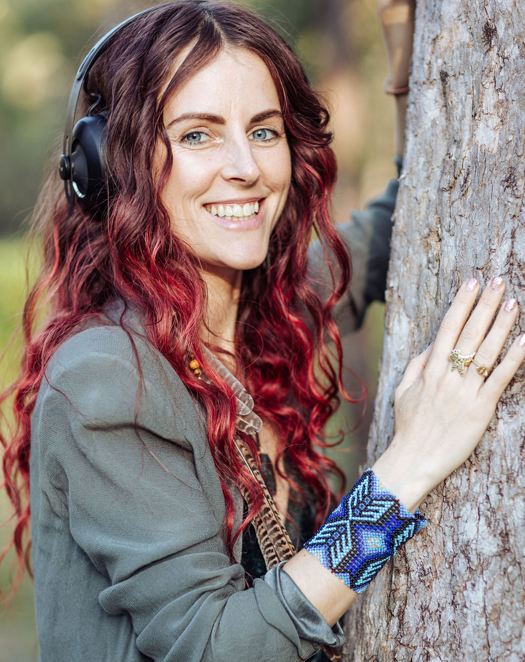Akela Bloom Akela smiling with hand on a tree trunk