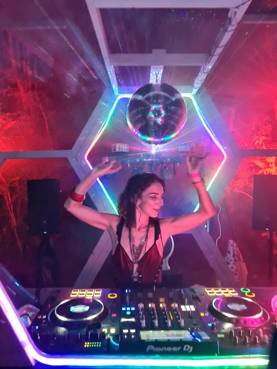 RIA Listic Ria on decks hands up in air dancing with lighting behind